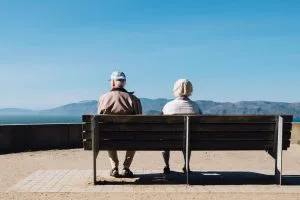 Collaborative Divorce. Dividing retirement Accounts. Old man and women sitting on bench and looking at mountains.