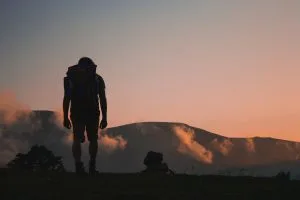 Parent Not Exercising Custody Rights. Silhouette of man walking on field leading to mountain at sunrise. Mukuko Studio (Unsplash)