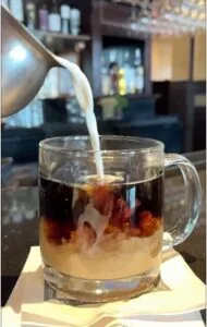 Cream being poured into black coffee commingling